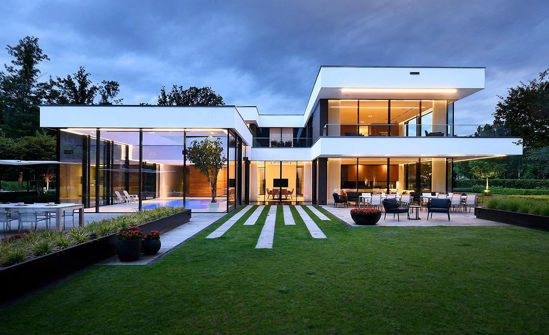 Contemporary villa at dusk with a lit glass façade